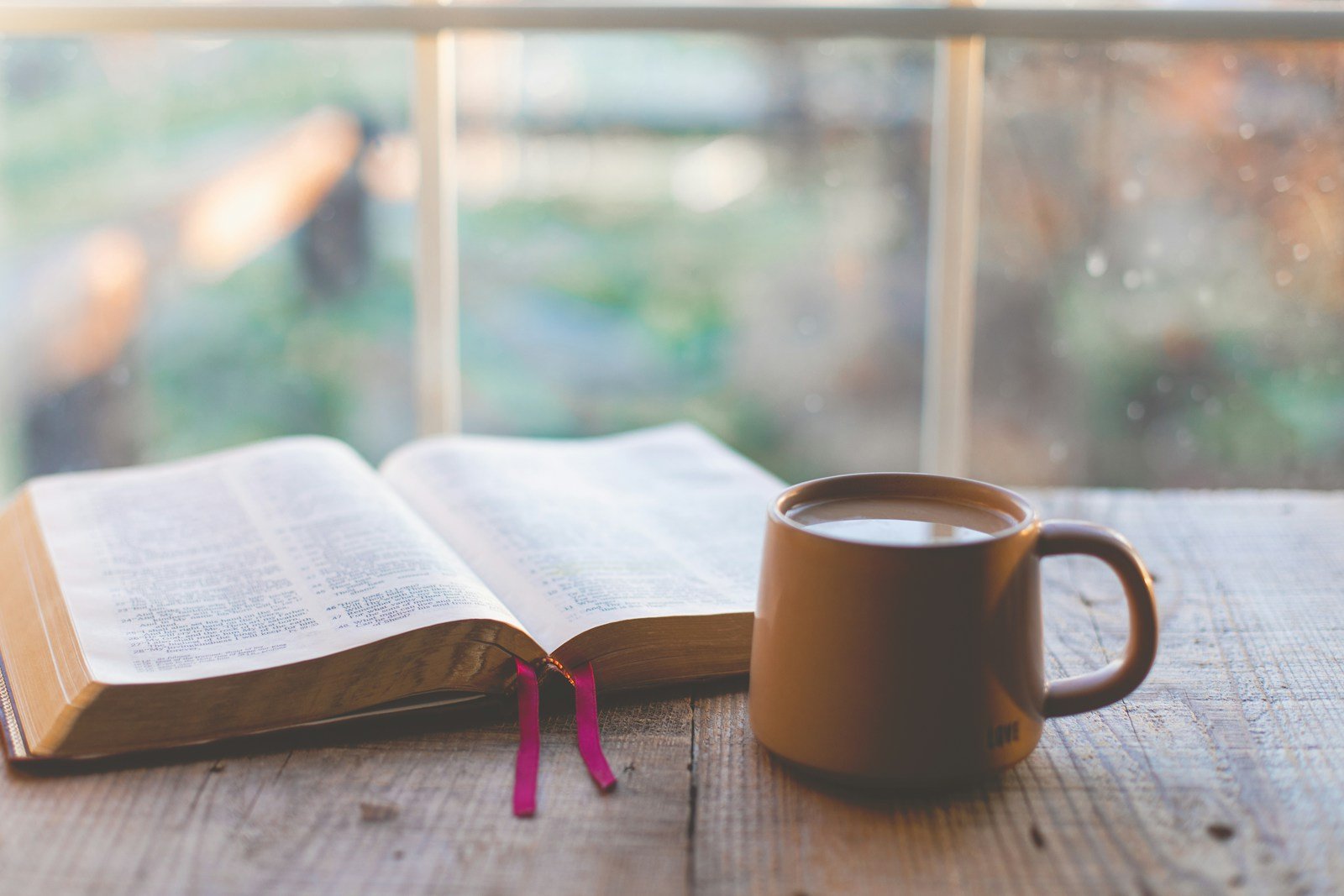 Livro aberto e café para mensagem de bom dia com versículo bíblico