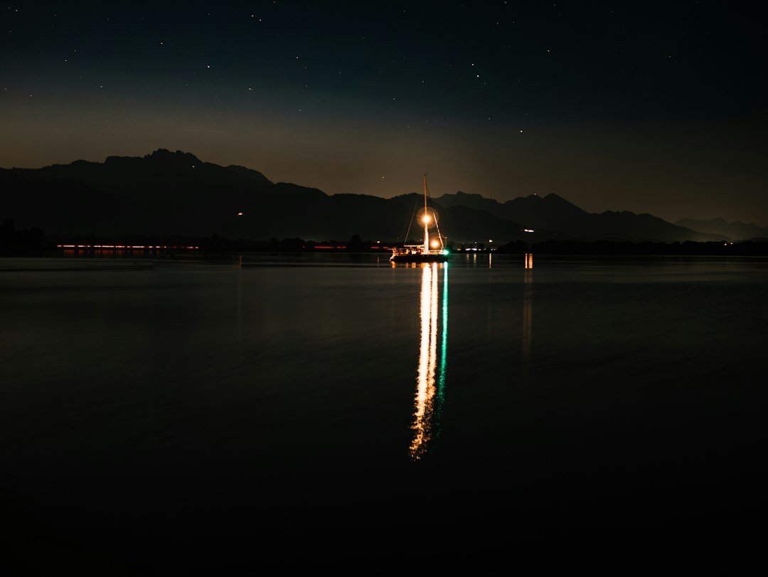 Mensagem de Boa Noite com Sabedoria: 42 Reflexões 1 Barco iluminado refletido em um lago calmo durante a noite