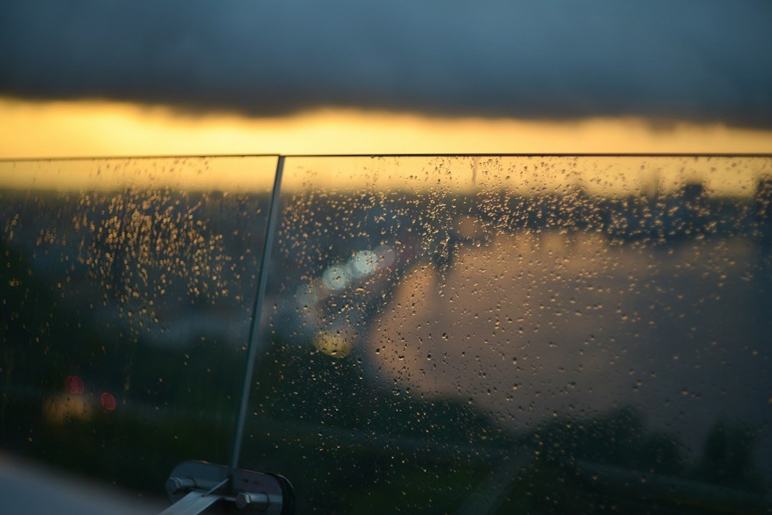 Mensagem de Bom Dia com Chuva: 45 Frases Aconchegantes 1 Gotas de chuva no vidro com luz suave ao fundo